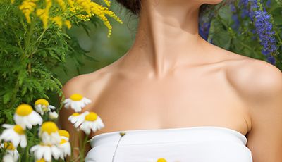 Woman surrounded by chamomile flowers in a garden — natural azulene extract skincare ingredient for ORY Skincare.