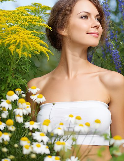 Woman surrounded by chamomile flowers in a garden — natural azulene extract skincare ingredient for ORY Skincare.