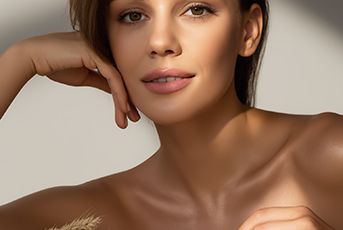 Woman with radiant skin beside natural grains representing Ferulic Acid antioxidant benefits in ORY Skincare formulations.