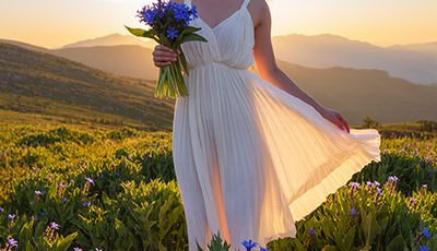 Woman holding blue borage flowers in a mountain meadow at sunset — natural borage seed oil skincare ingredient for ORY Skincare.