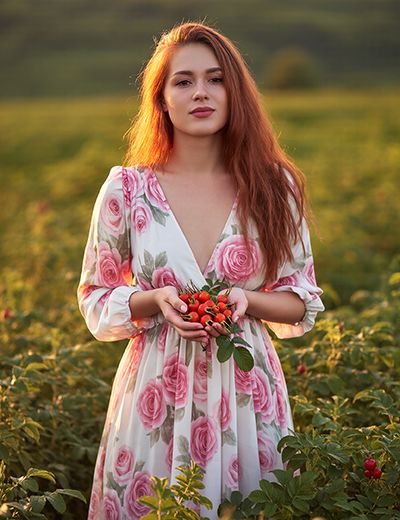 Woman holding fresh rosehips in a field, representing rosehip extract as a natural ORY Skincare ingredient rich in antioxidants and skin-nourishing nutrients.