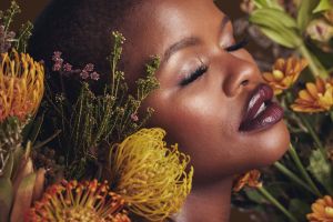 Serene portrait of a woman with glowing skin surrounded by warm-toned botanicals, illustrating the emotional and psychological influence of color in skincare rituals.
